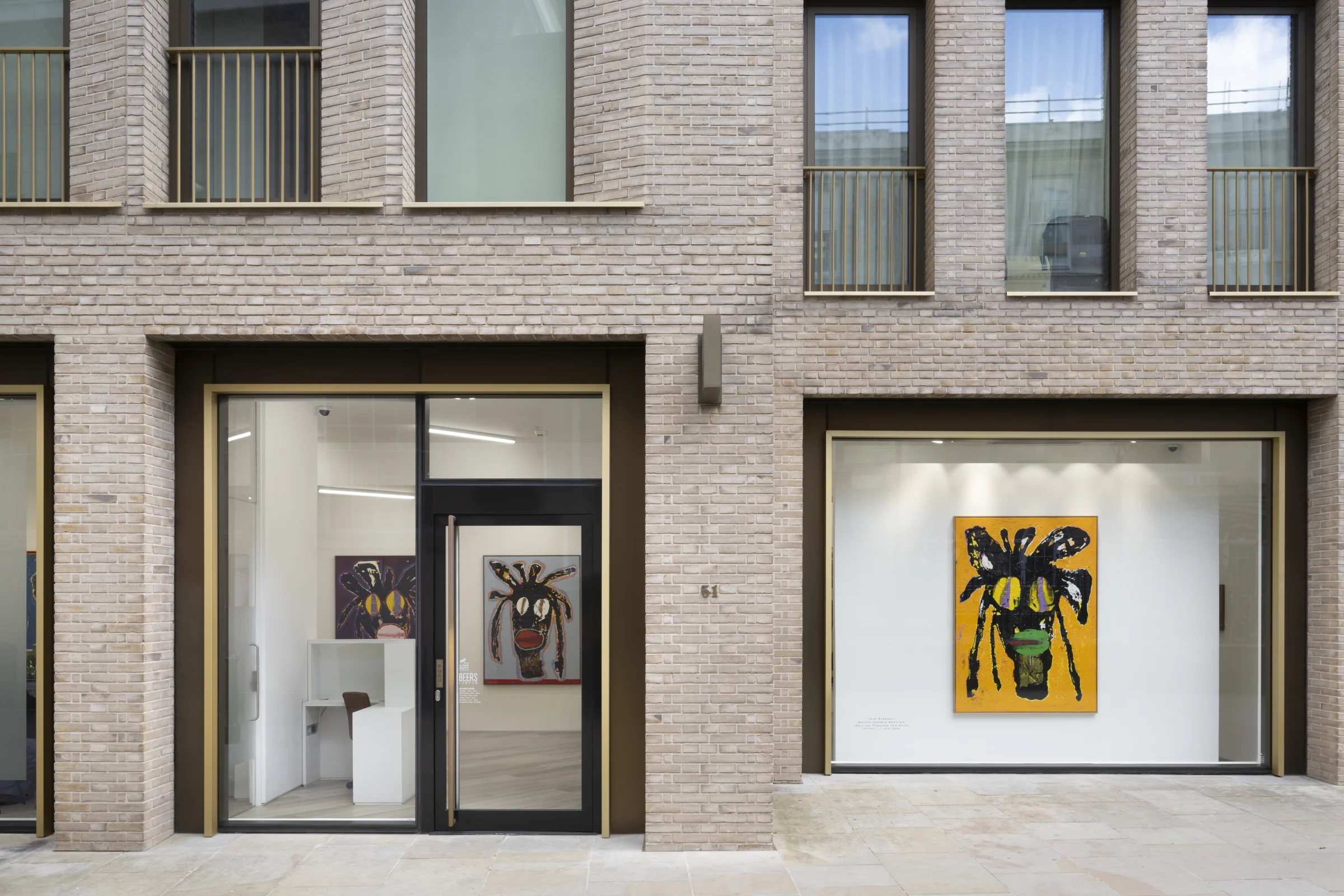 Contemporary art gallery exterior with bold paintings visible through large windows.