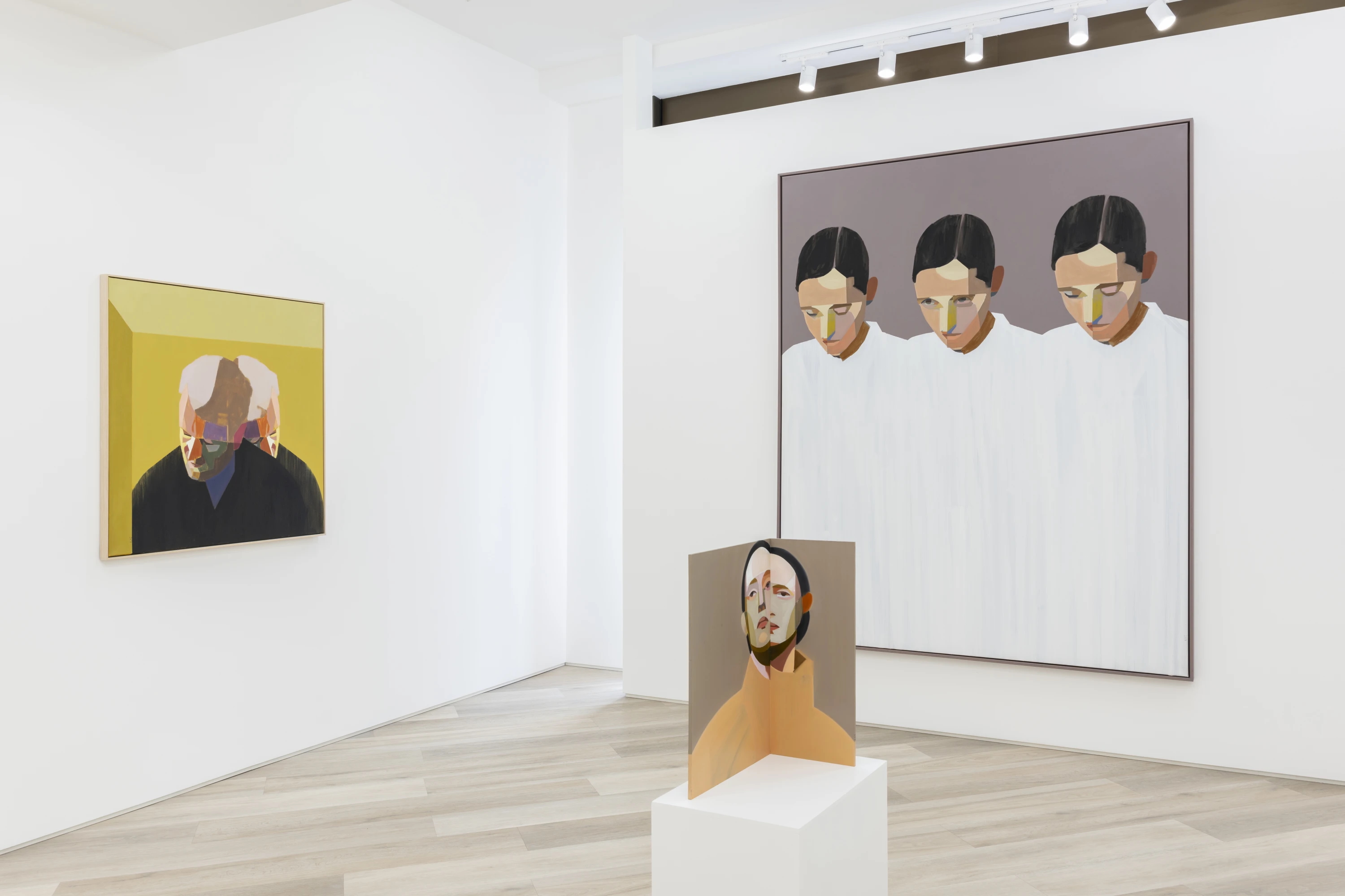 Minimalist gallery space showcasing abstract portrait paintings and a sculptural face study.